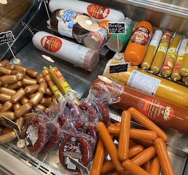 An assortment of deli meats and sausages displayed in a refrigerated case